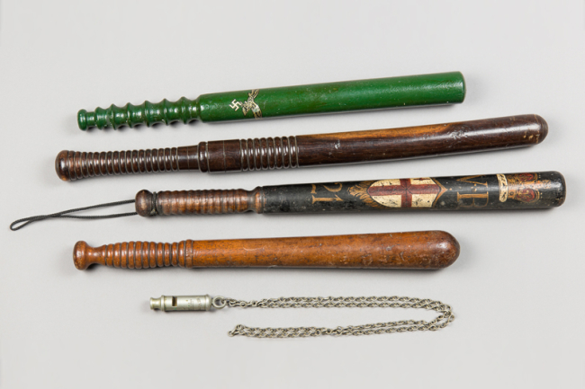 A collection of four wood police and military truncheons, along with a police whistle on chain lanyard. Price realised £200